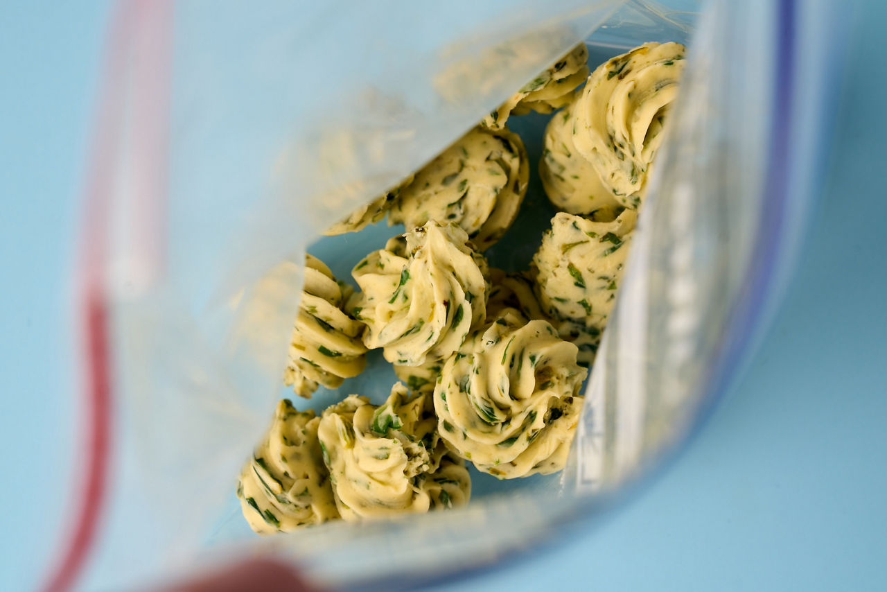 Petits morceaux de beurre persillé dans une boîte de conservation.