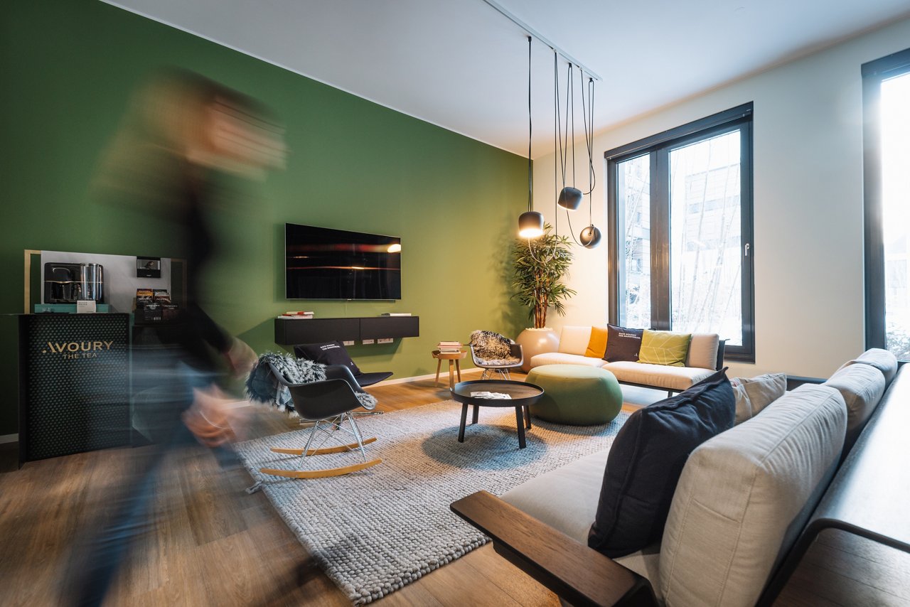 Modern lounge corner with sofa and armchairs in different shades of green.