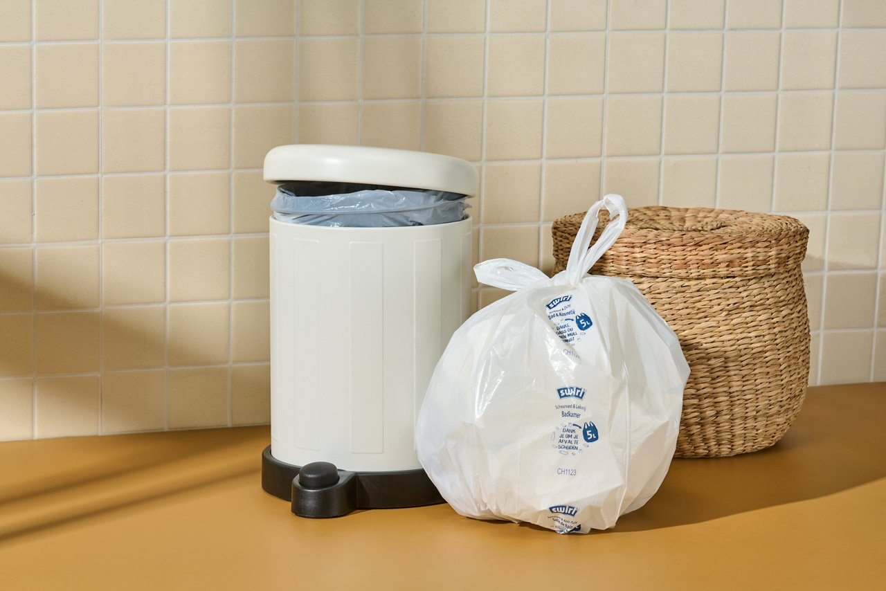 Gefüllter 5L Swirl Bad & Kosmetikbeutel steht vor Mülleimer