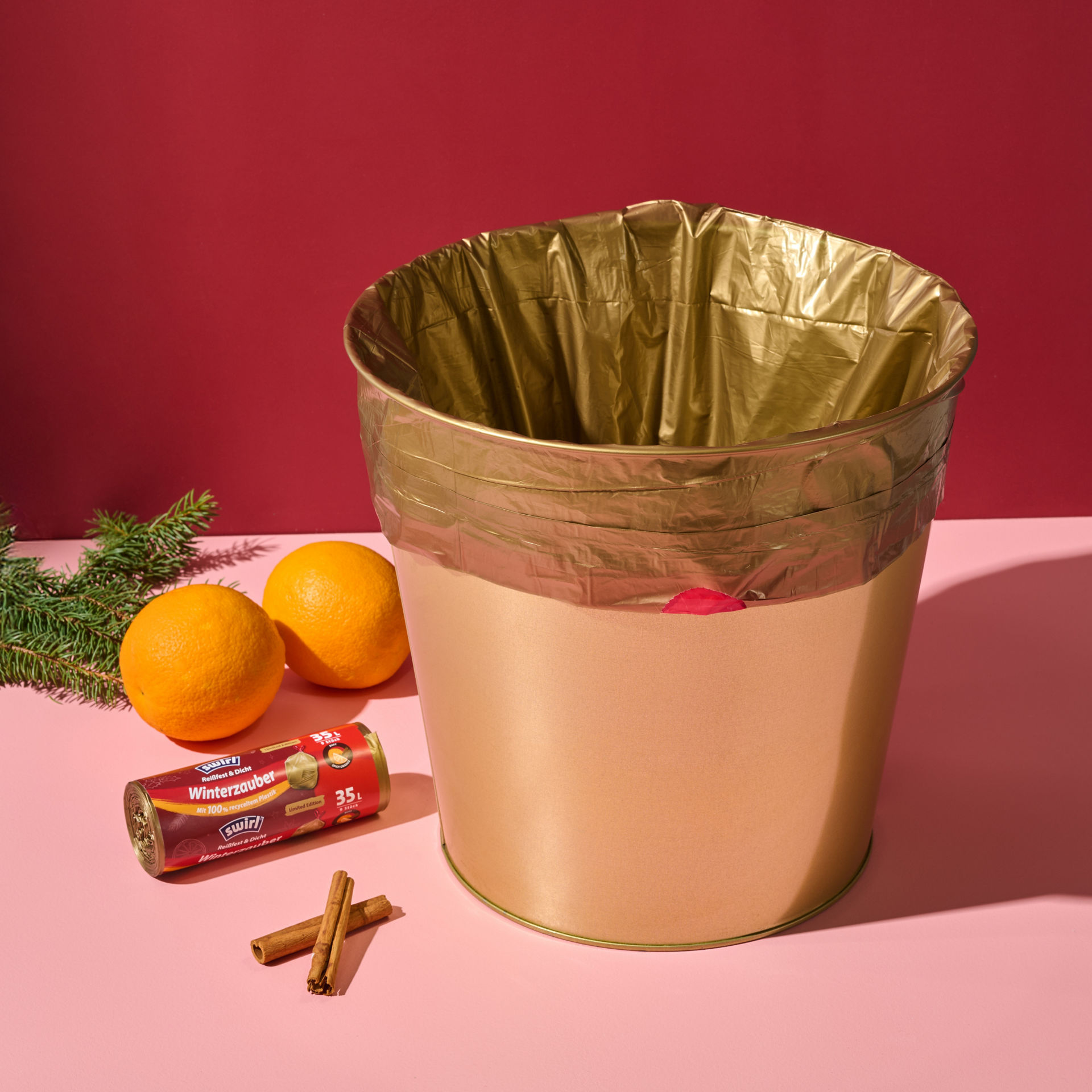 Goldener Mülleimer mit goldenem Swirl Winterzauber Müllbeutel steht neben winterlichen Accessoires