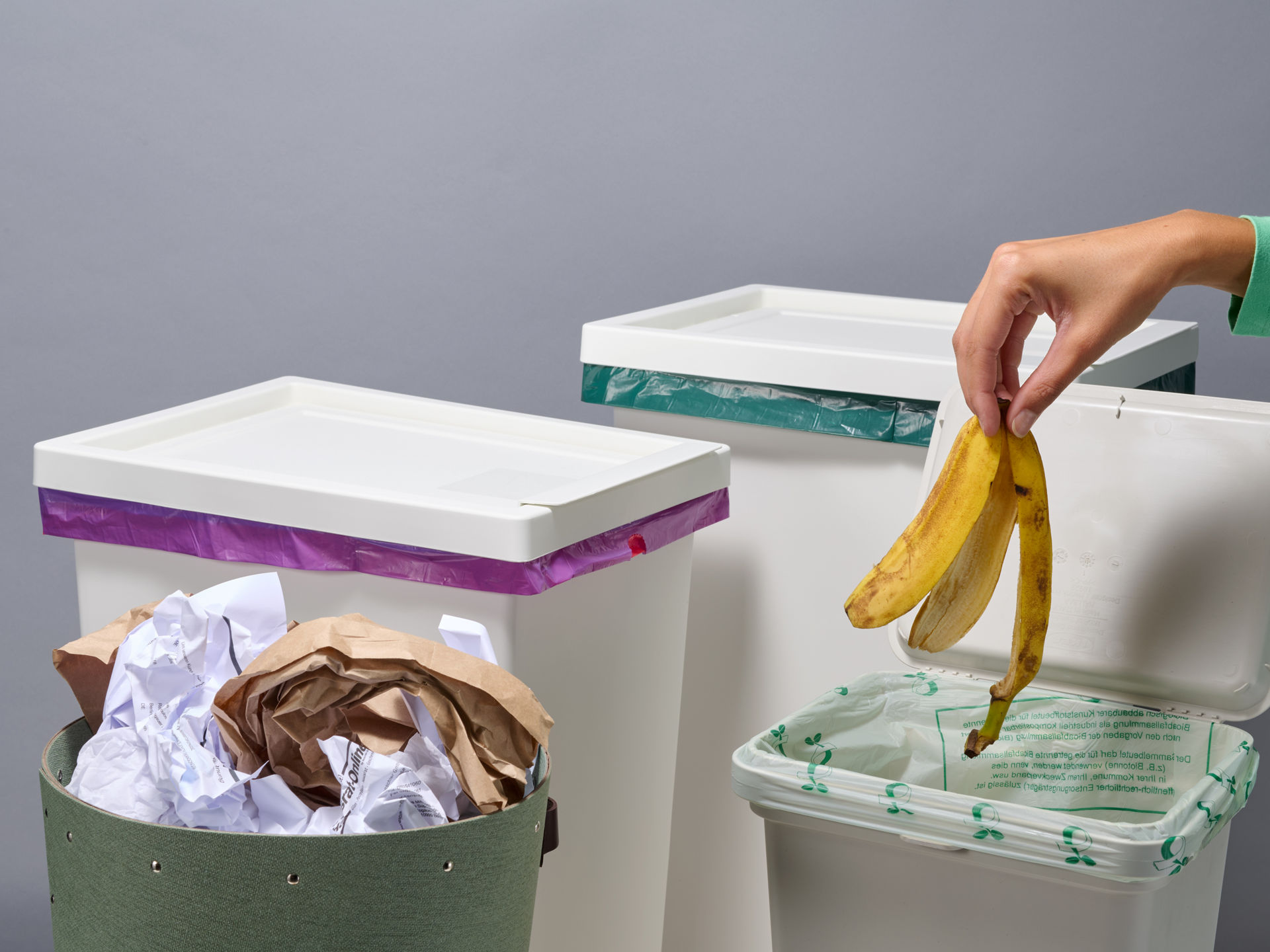 Vier verschiedene Mülleimer und Müllarten, Hand entsorgt Bananenschale in den Biomüll