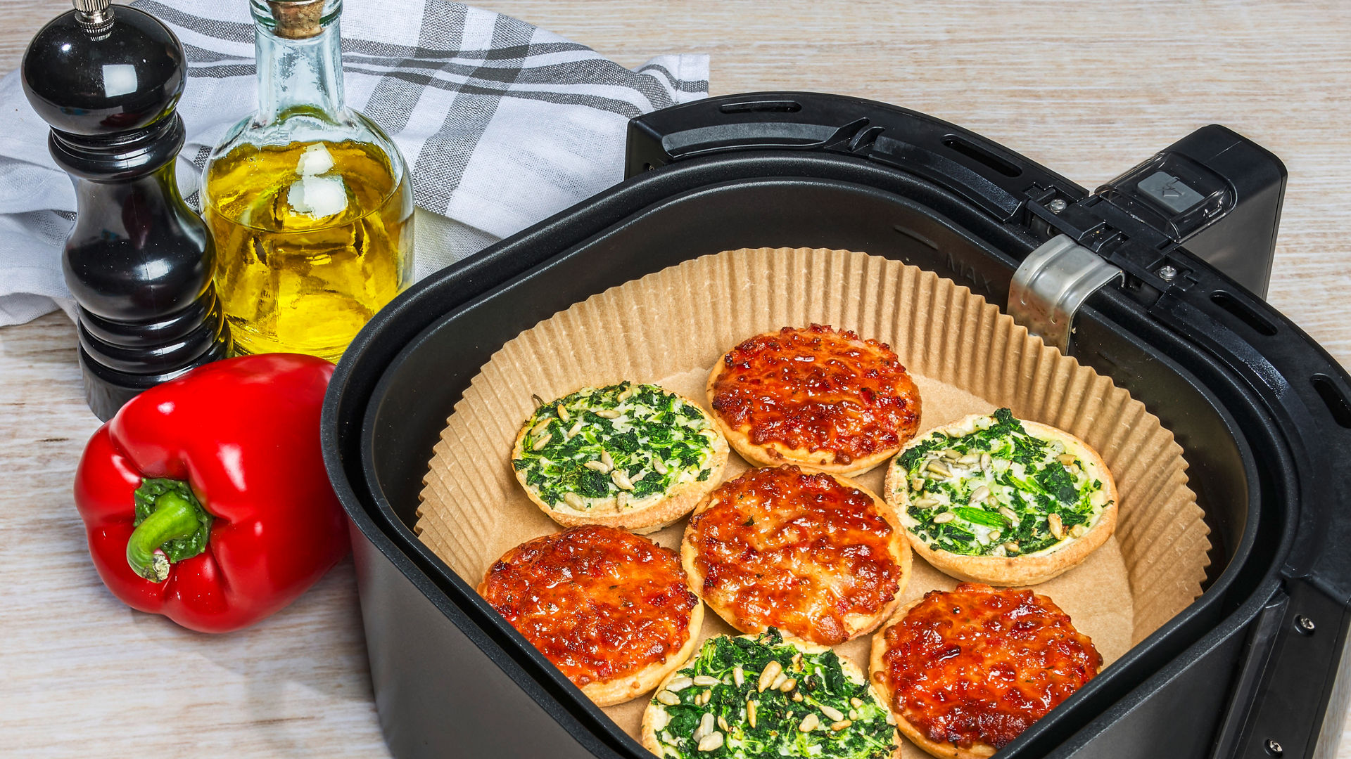 Mini-Pizzen mit Spinat und Tomate auf Toppits Backpapier in der Heißluftfritteuse, frische Zutaten.