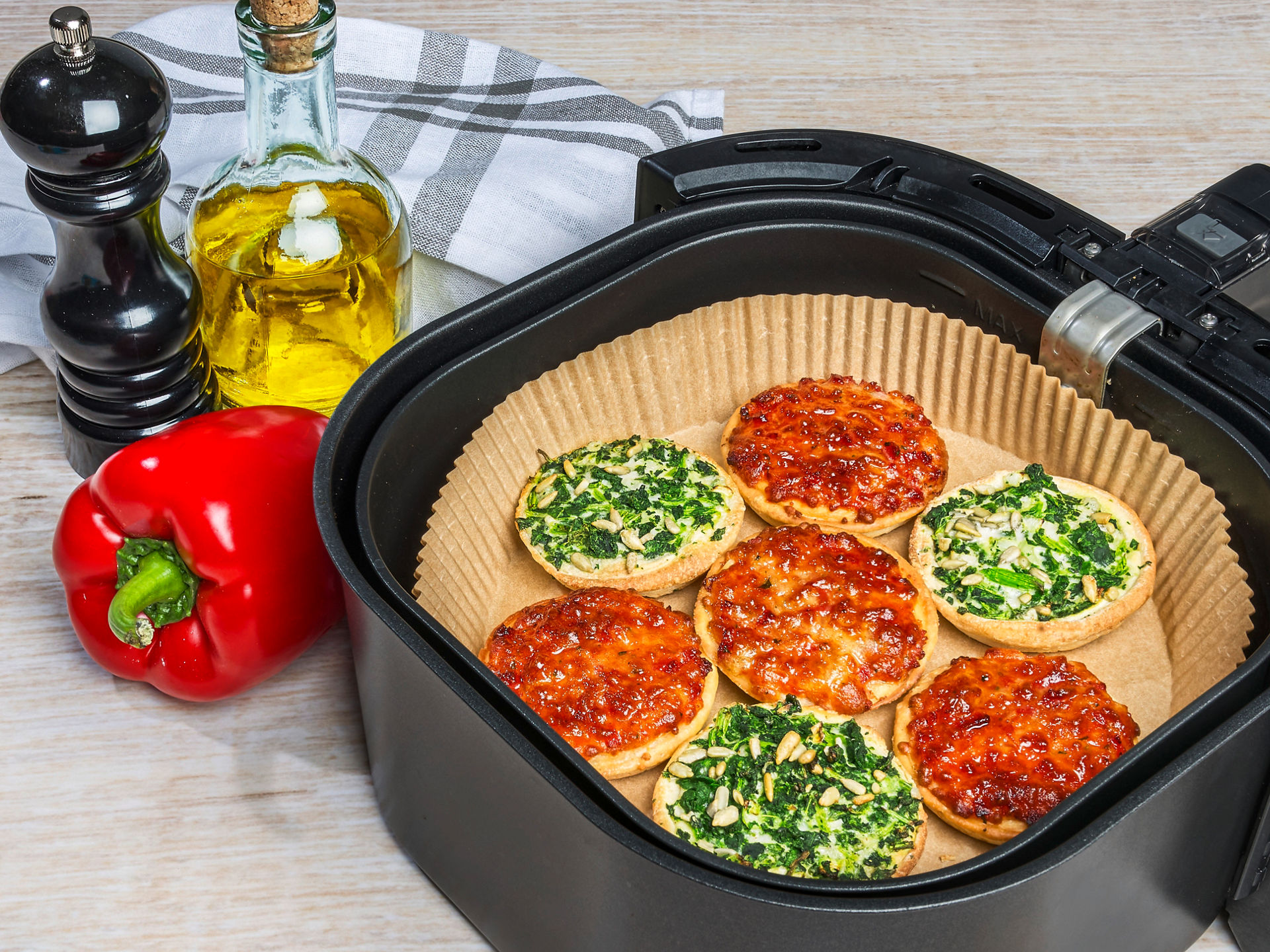 Mini-Pizzen mit Spinat und Tomate auf Toppits Backpapier in der Heißluftfritteuse, frische Zutaten.