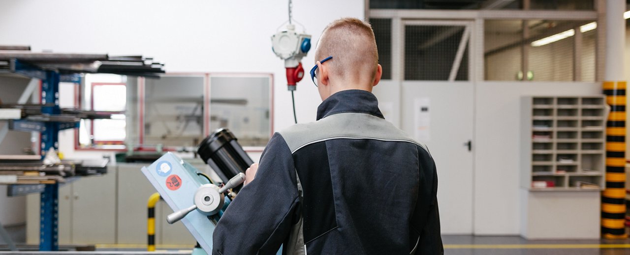 Young, blond-haired man in work clothes tinkering in training workshop