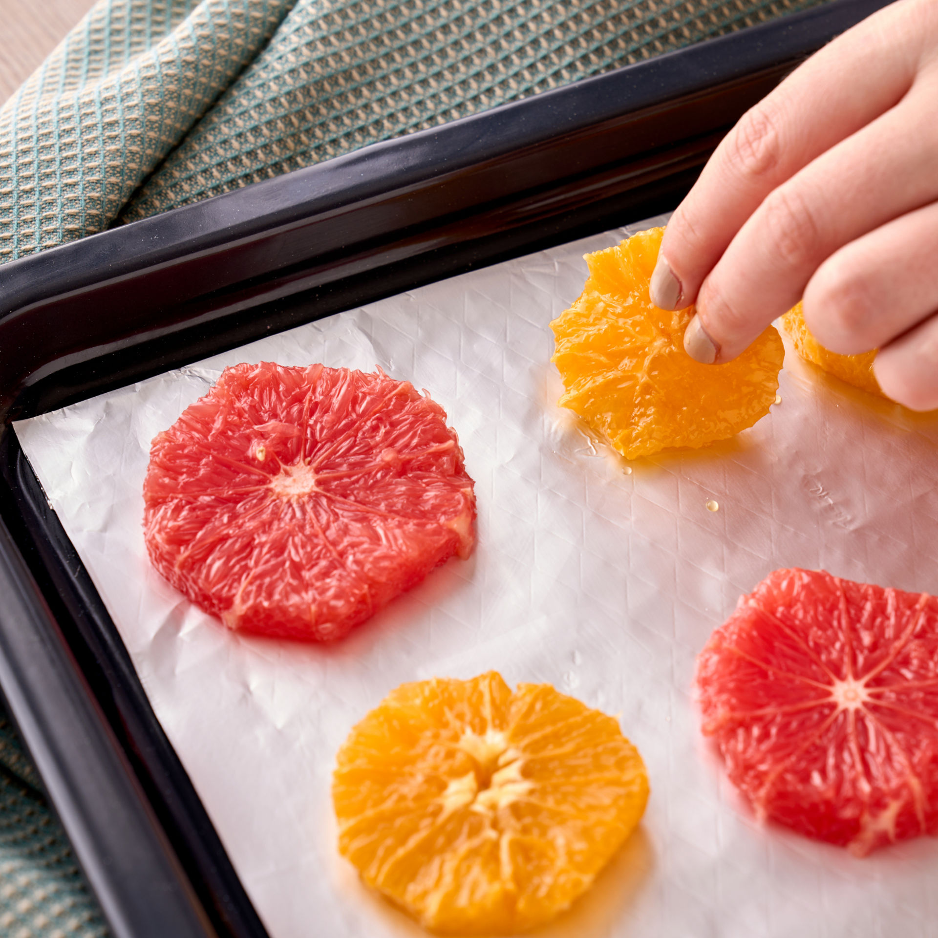 Orangen- und Grapefruitscheiben liegen auf einem Backblech mit Toppits Back-Alufolie.