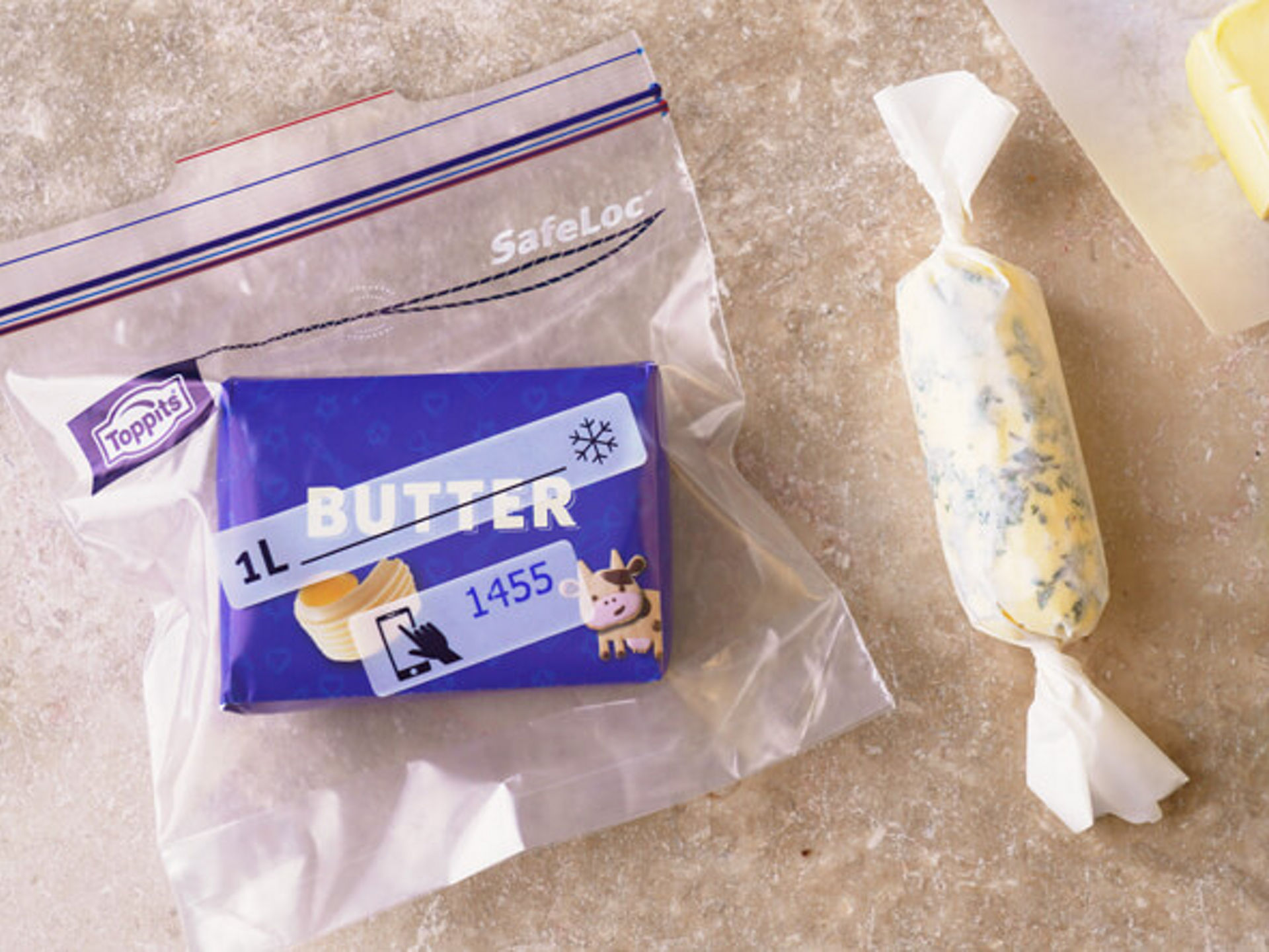 Verpackte Butter in Toppits SafeLoc Beutel neben Kräuterbutter und frischen Kräutern