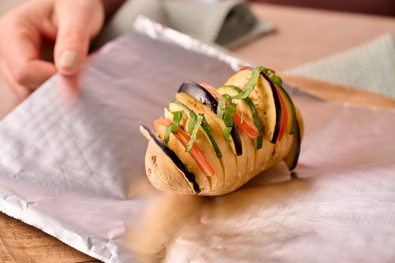omme de terre au four avec des légumes et des herbes, préparée sur du papier aluminium Toppits
