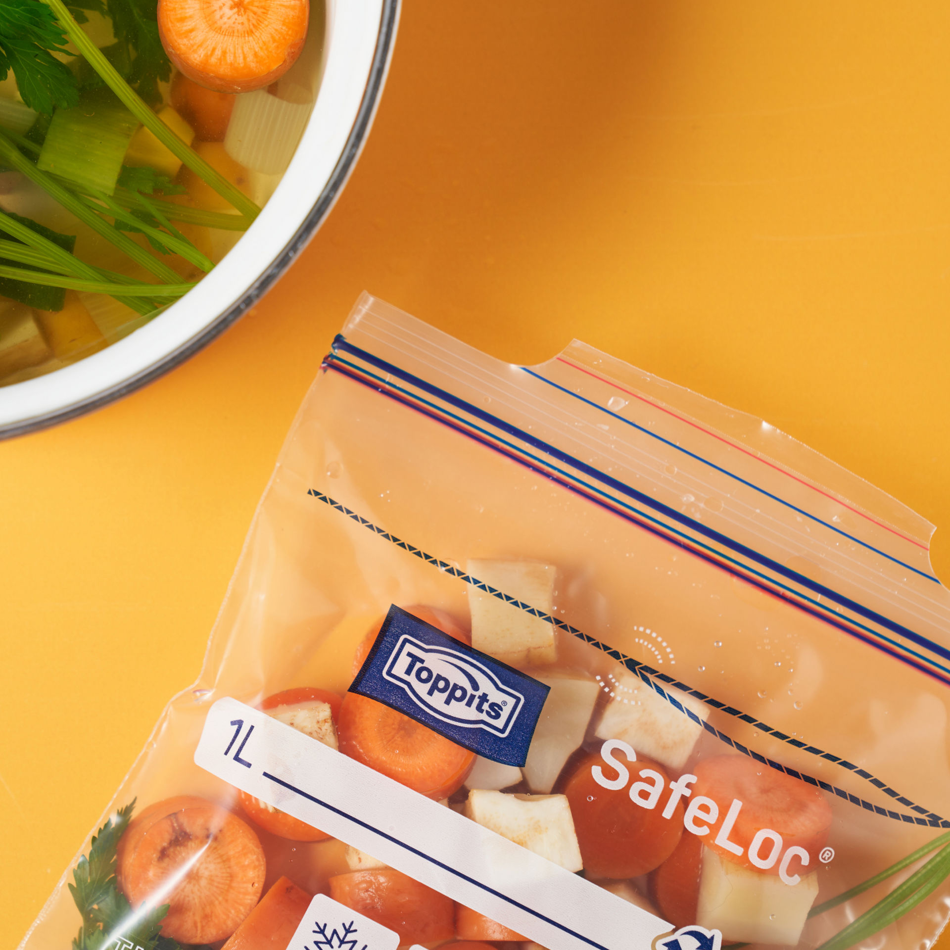 Sacs Toppits® SafeLoc® contenant des légumes, posés à côté d’une assiette jaune.