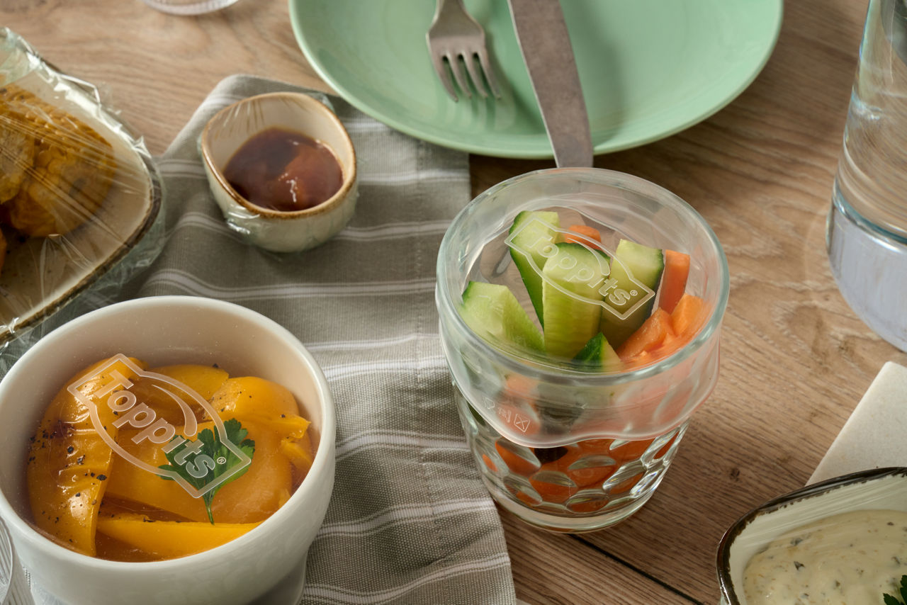 Bols recouverts de couvercles extensibles Toppits® Stretch Tops, avec légumes, sur une table dressée.