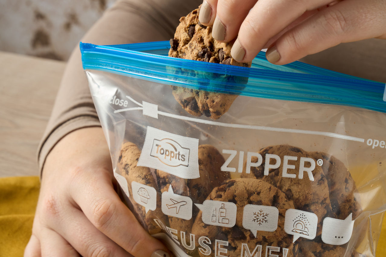 Une main tient un sac Toppits® Zipper® rempli de biscuits faits maison.