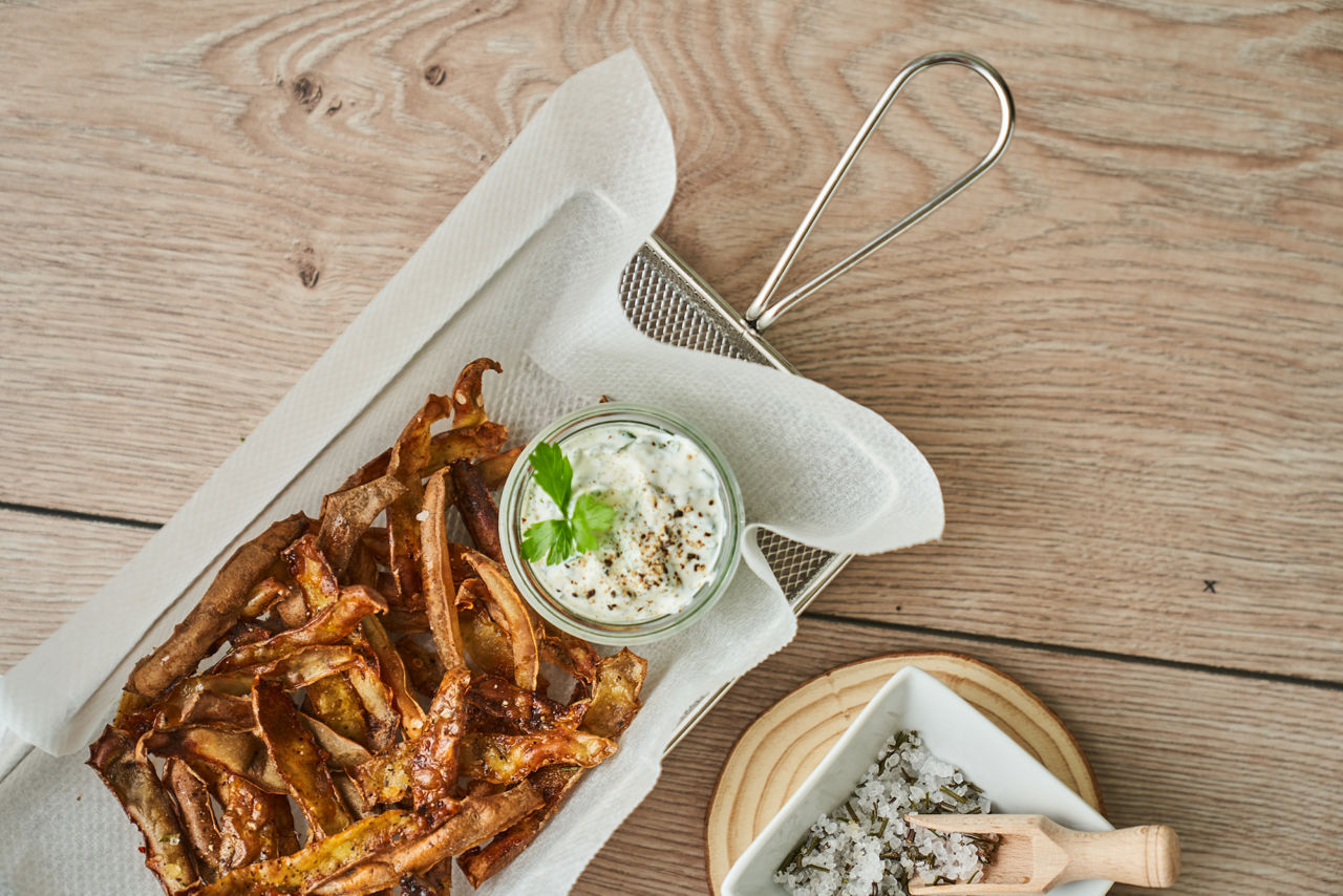 Knusprige Kartoffelschalen-Chips mit Dip auf Toppits Cross & Frit Papier in einer Frittierform.