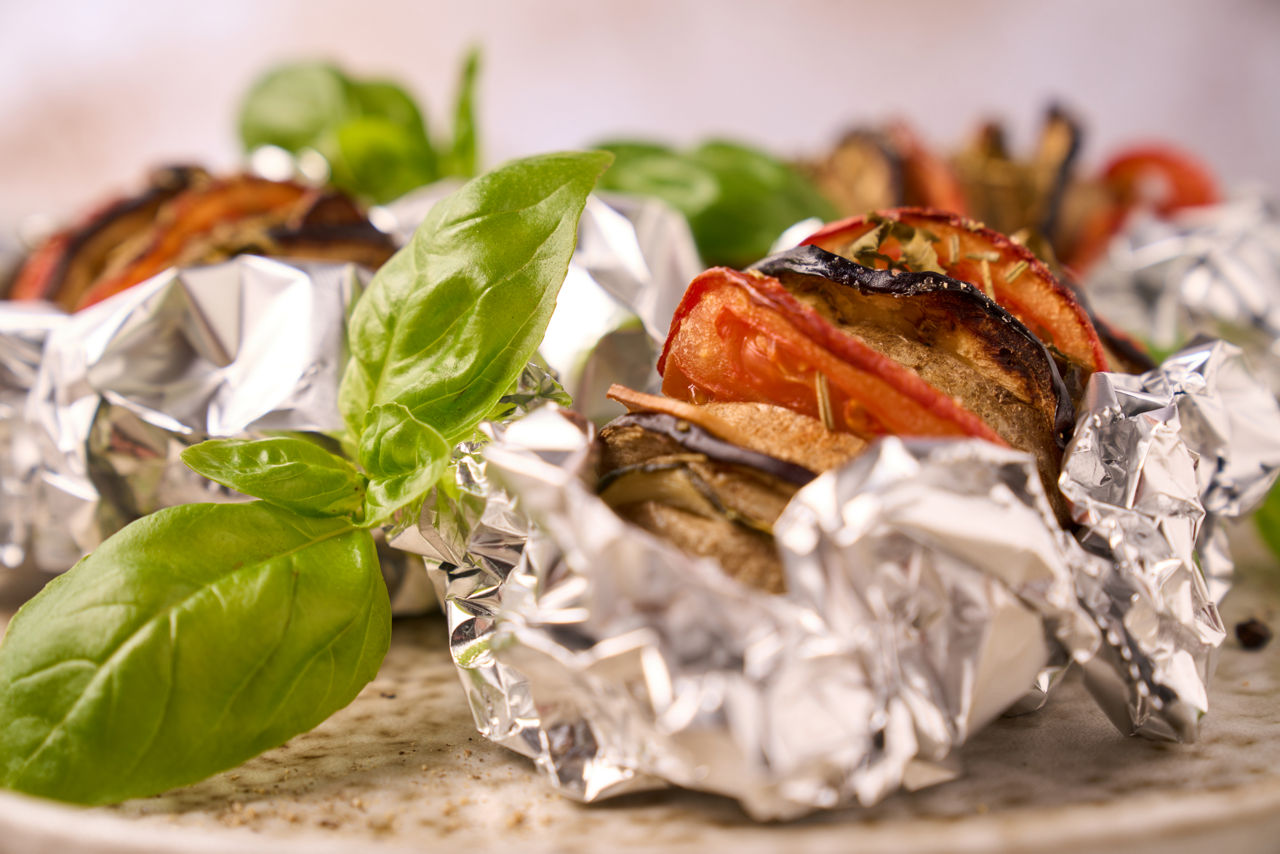 Fyldt kartoffel med grillgrøntsager, pyntet med basilikum, i aluminiumsfolie