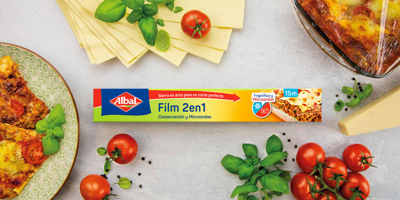Film 2 en 1 para conservación y microondas, rodeado de ingredientes frescos y lasaña en una bandeja de cristal.