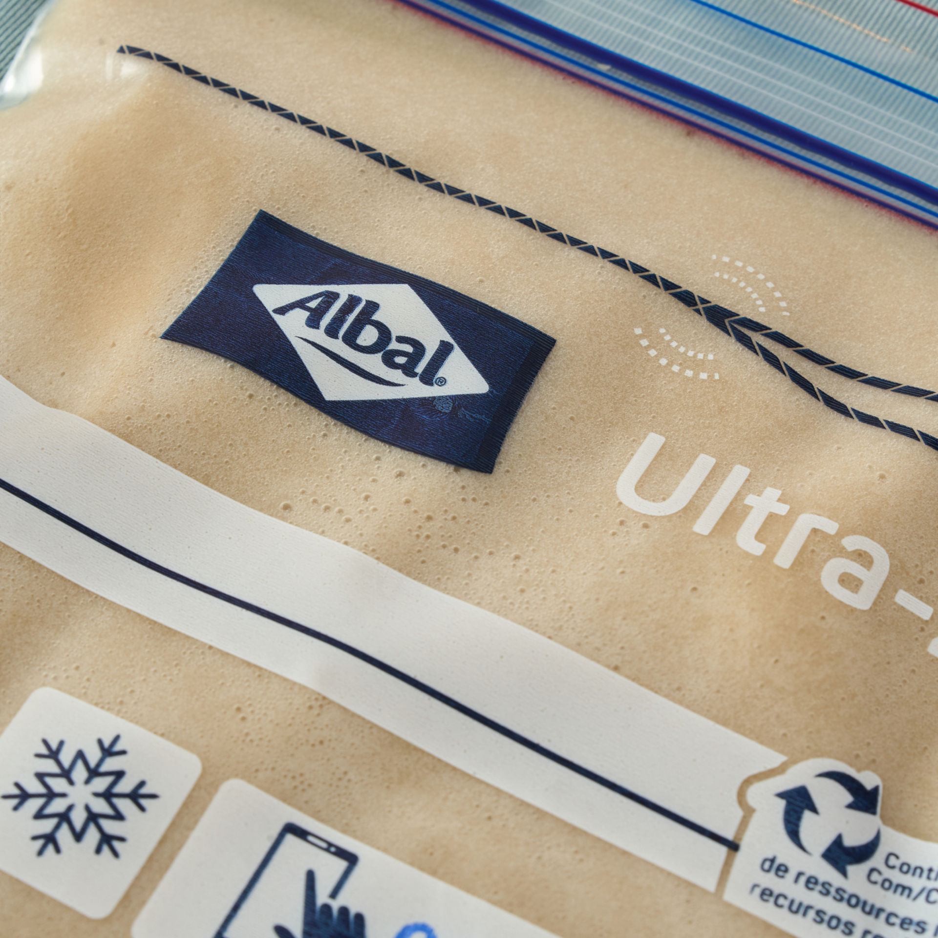 Primer plano de una bolsa de cierre hermético con masa líquida en su interior sobre fondo azul claro.