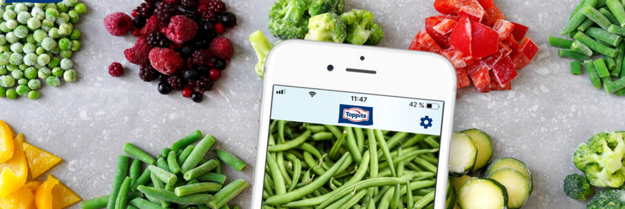 Foodsaver App auf Smartphone, umgeben von gefrorenem Gemüse und Beeren von Toppits.