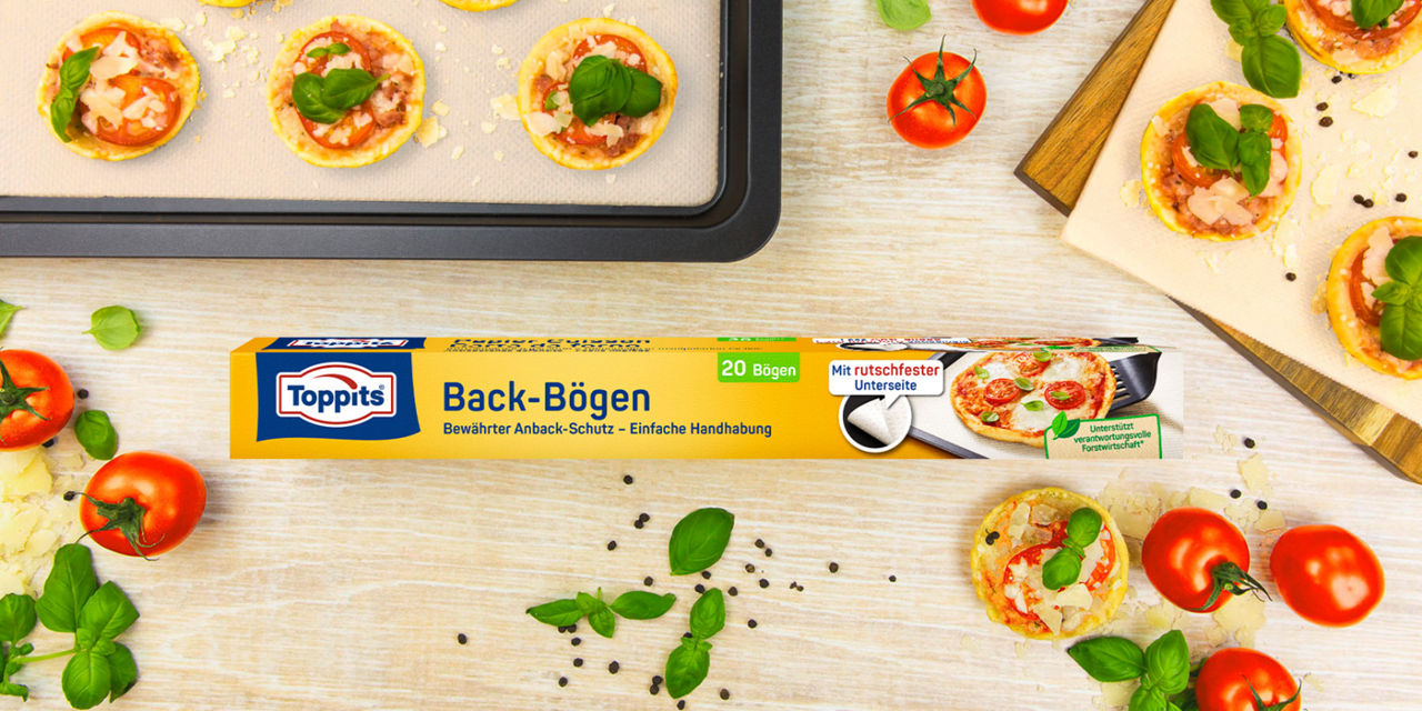Toppits Back-Bögen mit Mini-Pizzen auf Backblech, frische Tomaten und Basilikum.