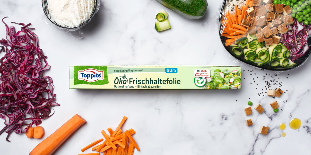 Toppits Öko Frischhaltefolie mit einer bunten Bowl, Reis und Gemüse auf weißem Untergrund, hergestellt aus recycelten Ressourcen.