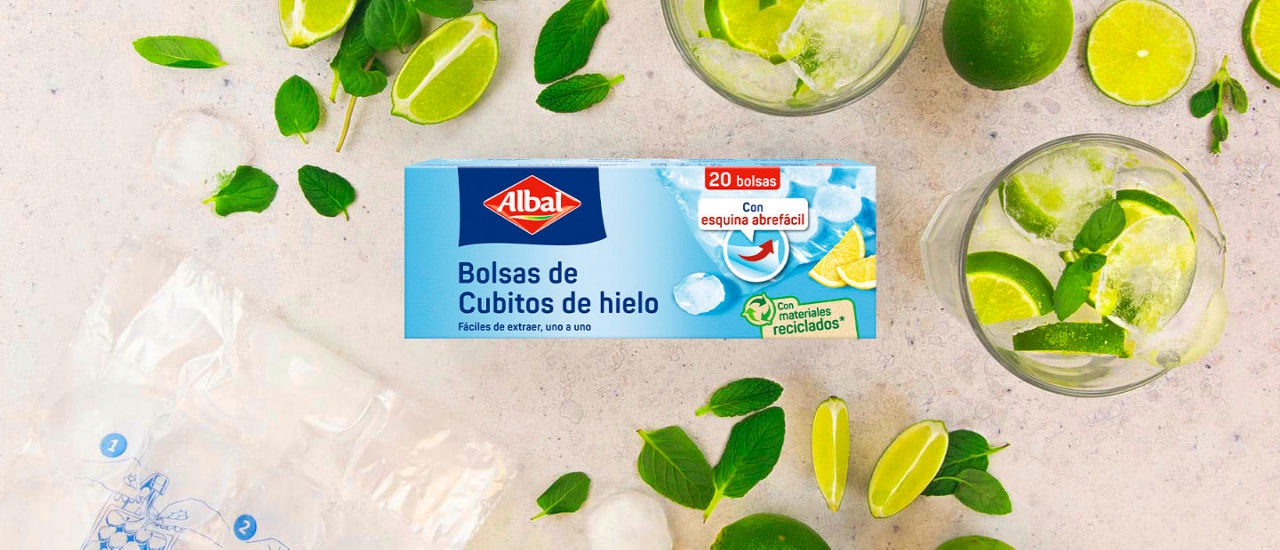 Caja de bolsas para cubitos de hielo Albal sobre una mesa, rodeada de limas, hojas de menta, vasos con hielo y cubitos de hielo