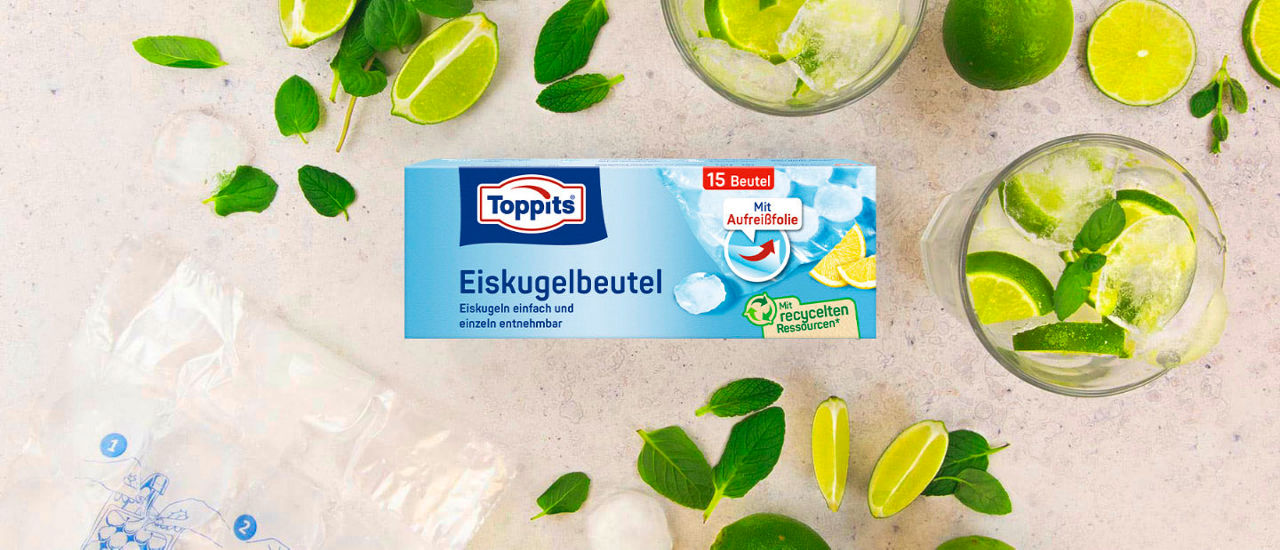 Toppits Eiskugelbeutel-Packung, umgeben von Limetten, Minze, Eiswürfeln und zwei Gläsern mit Getränk