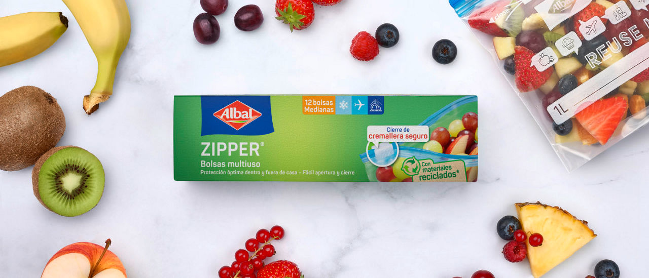 Caja de bolsas multiuso con cierre zipper Albal sobre una mesa, rodeada de frutas frescas y una bolsa transparente con mezcla de frutas