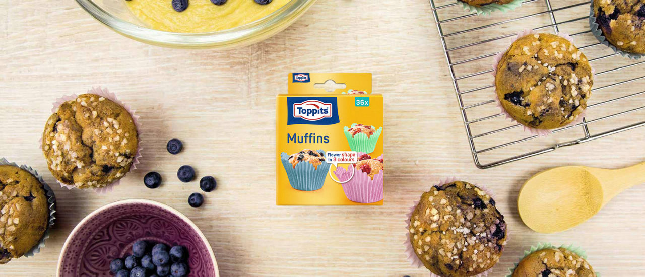 Verpackung der Toppits Flower Muffins auf Holzuntergrund mit Essen durmherum