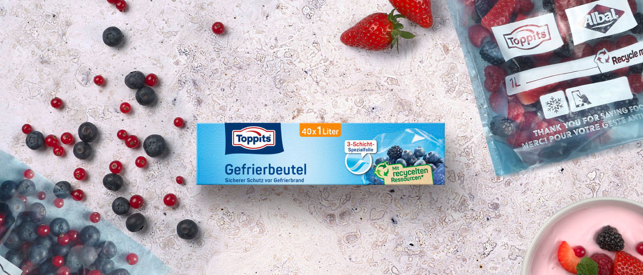 Packung Toppits Gefrierbeutel, umgeben von Beeren und einem gefüllten Gefrierbeutel