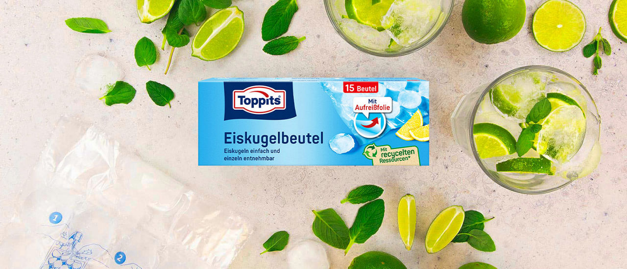 Toppits Eiskugelbeutel-Packung, umgeben von Limetten, Minze, Eiswürfeln und zwei Gläsern mit Getränk