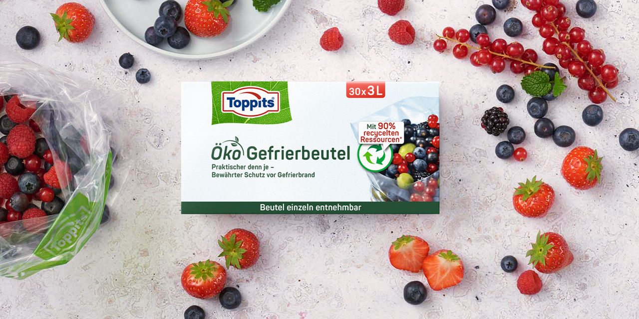 Packung Toppits Öko Gefrierbeutel, umgeben von frischen Beeren und einem geöffneten Gefrierbeutel mit Beeren.