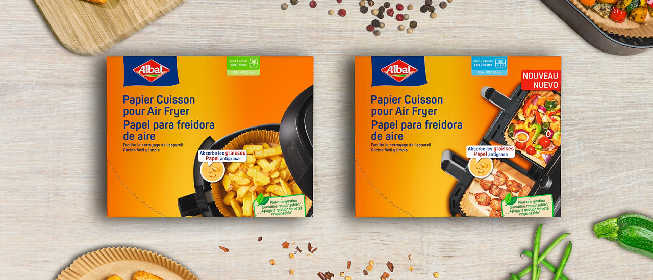 Dos cajas de papel para freidora de aire, rodeadas de palitos empanizados y verduras frescas.