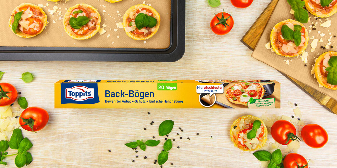 Toppits Back-Bögen mit Mini-Pizzen auf Backblech, frische Tomaten und Basilikum.