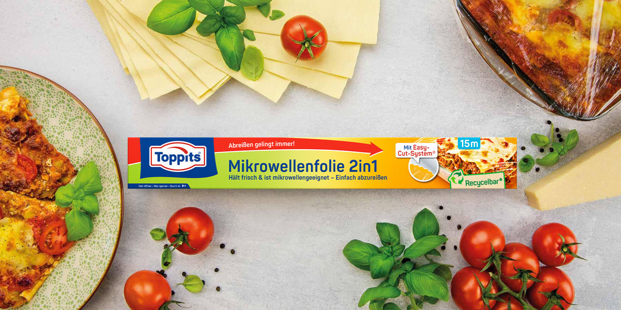 Toppits Mikrowellenfolie 2in1 mit Lasagne, frischen Tomaten, Basilikum und Käse auf Tisch.