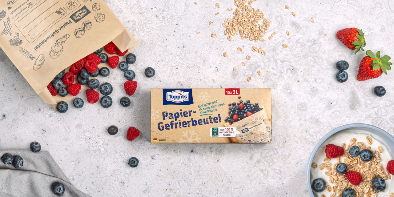 Toppits Papier-Gefrierbeutel mit Beeren, Haferflocken und Joghurt auf heller Steinoberfläche.
