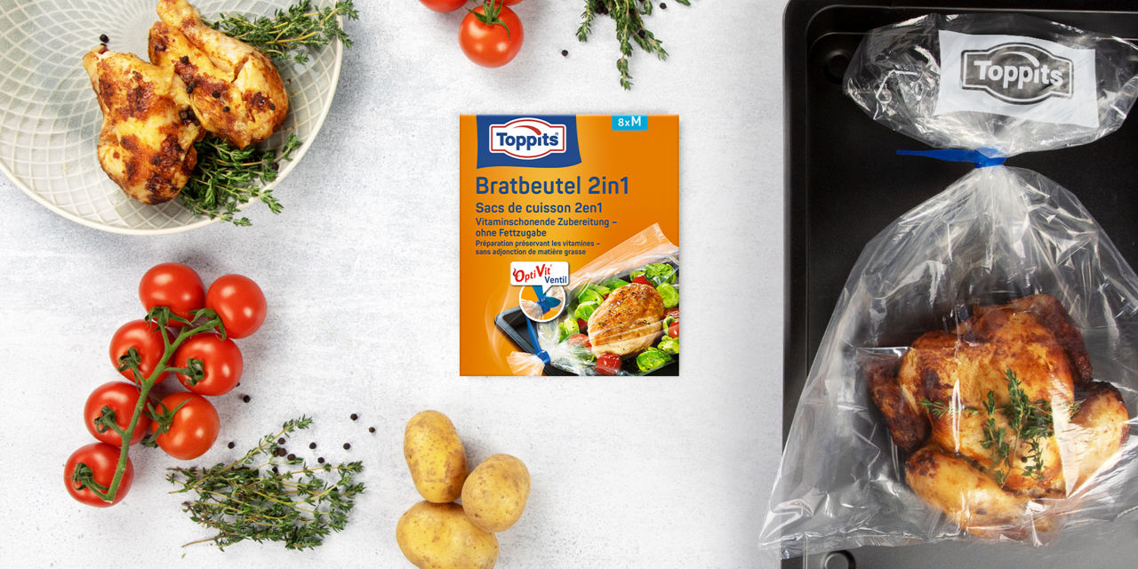    	 Toppits Bratbeutel 2in1 mit OptiVit Ventil, Hähnchen im Bratbeutel und frische Zutaten auf Tisch.