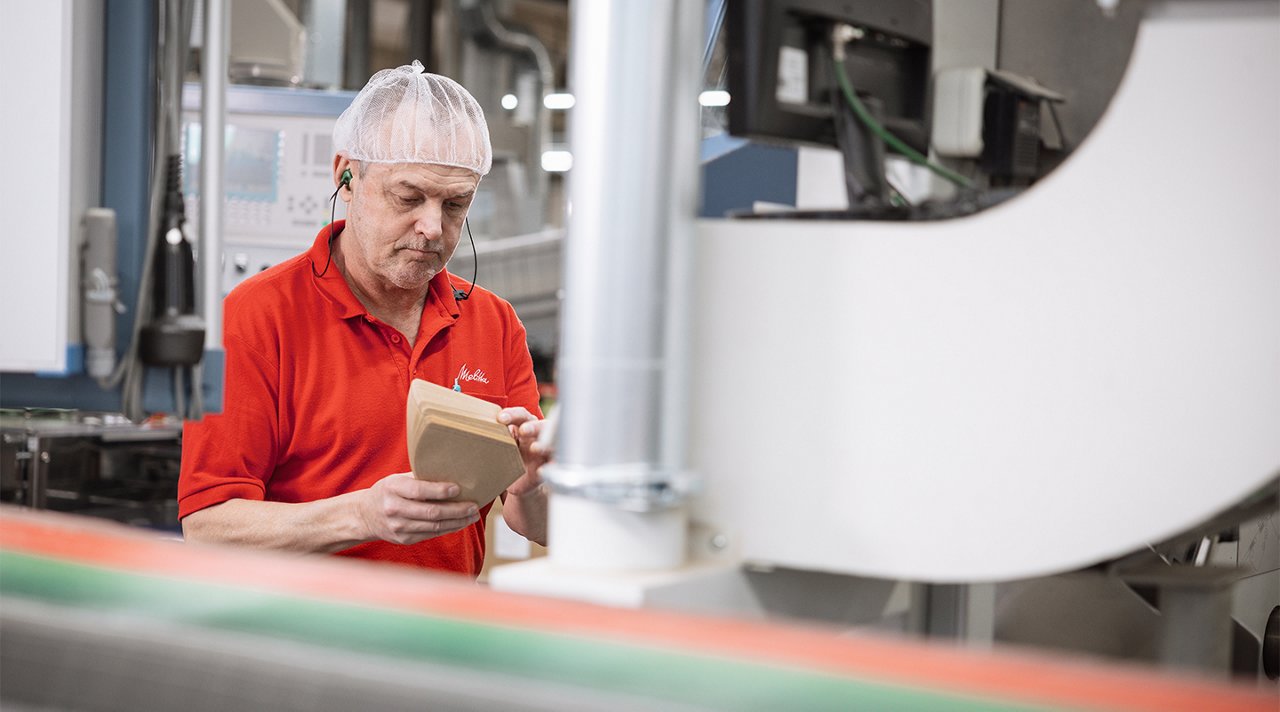 Melitta employee with red logo shirt in paper filter production
