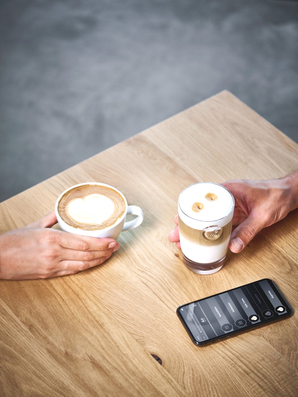 Zwei Kaffeespezialitäten mit Handy auf Tisch
