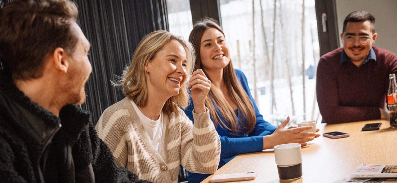 Vier Kollegen lachend am Küchentisch im Büro 