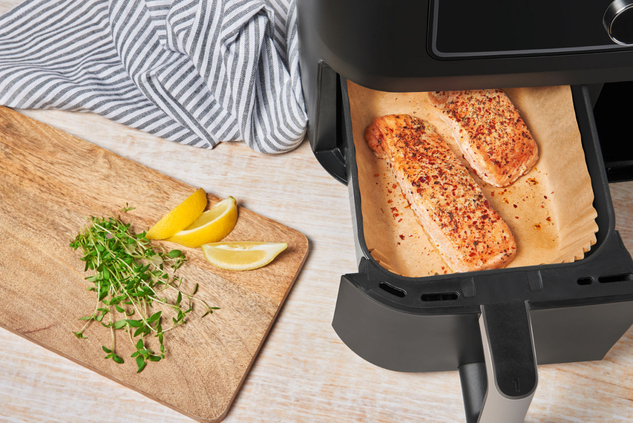 Salmón cocinándose en una freidora de aire sobre papel de hornear