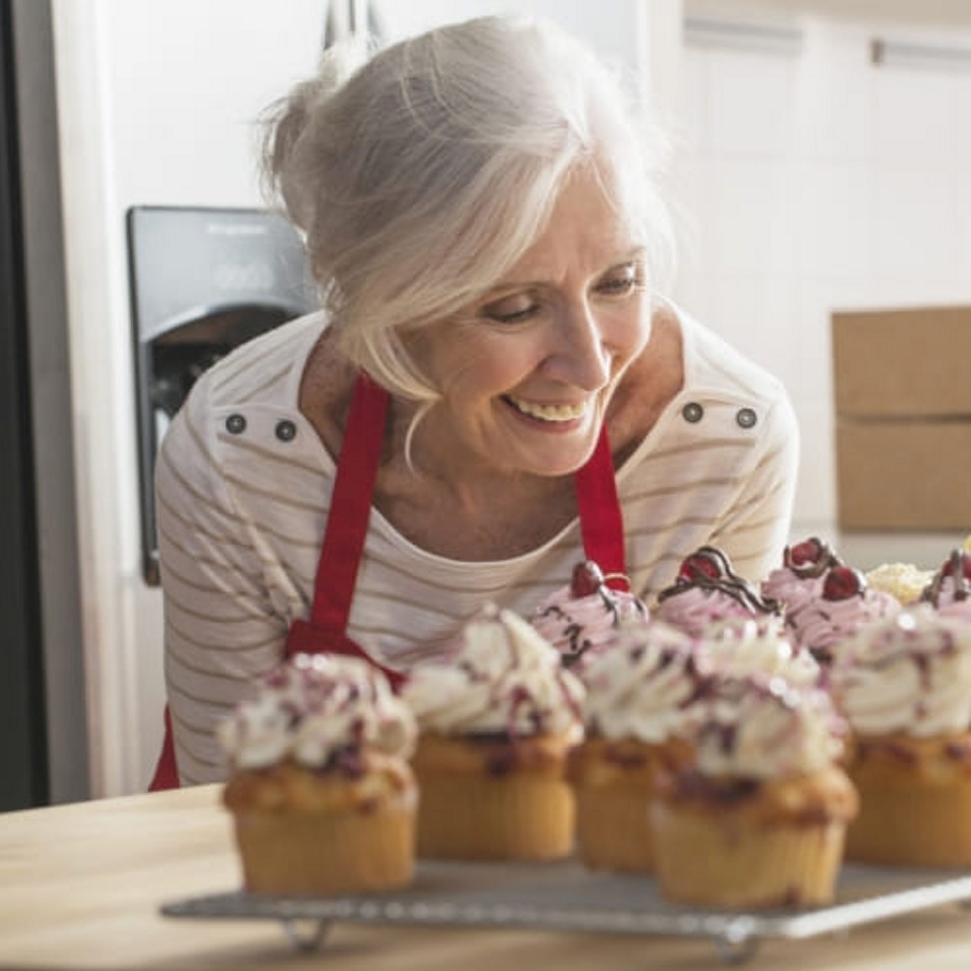 Older Caucasian woman with cupcakes in kitchen