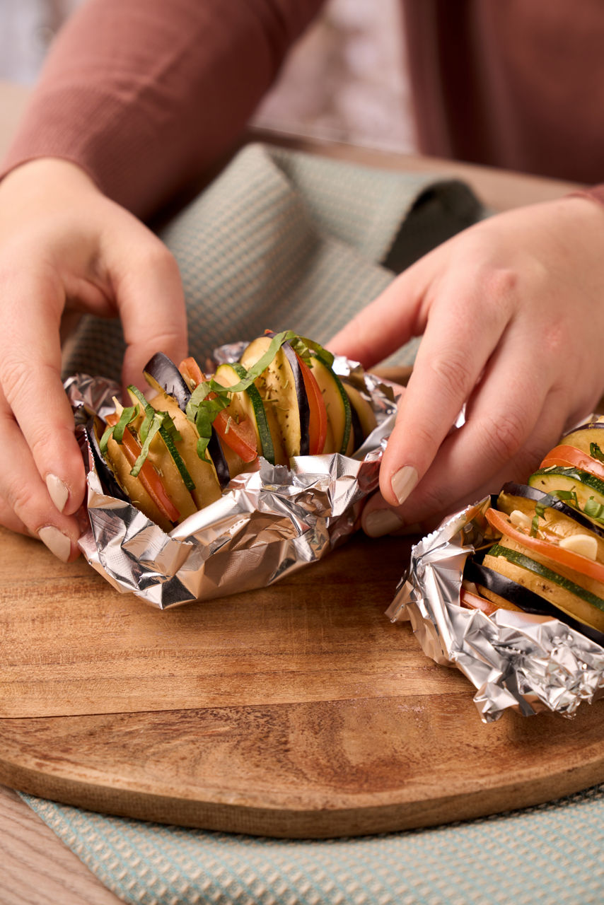 Person pakker inn grønnsaker i Toppits aluminiumsfolie.