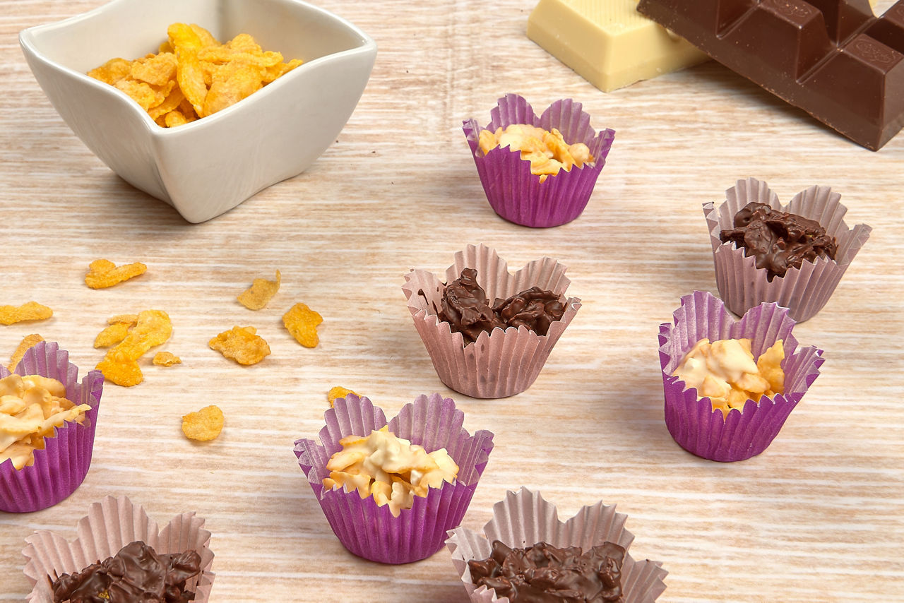 Cornflakes-Bites in Flower-Muffinförmchen stehen  auf einer Holzplatte