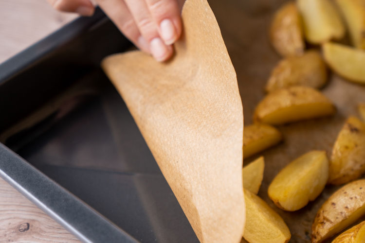 Retrait de papier cuisson Albal® brun avec des pommes de terre cuites d'une plaque de cuisson