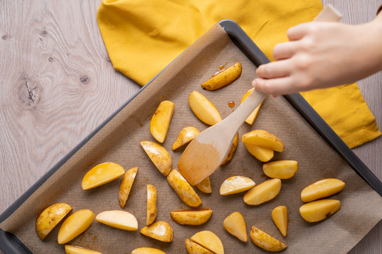 Quartiers de pommes de terre déposés sur une plaque de cuisson recouverte de papier cuisson Albal® brun