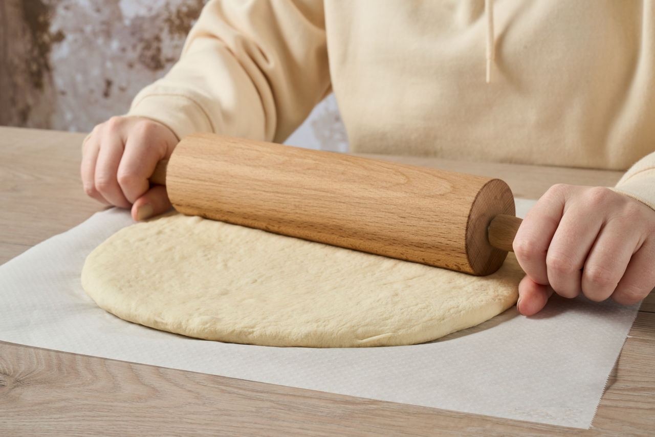 Pâte étalée sur du papier cuisson Albal® avec un rouleau à pâtisserie