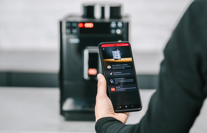Passione_Bild_neben_CollapseElement_CompanionApp1.png – Melitta® Passione model with app control interface in a home environment.