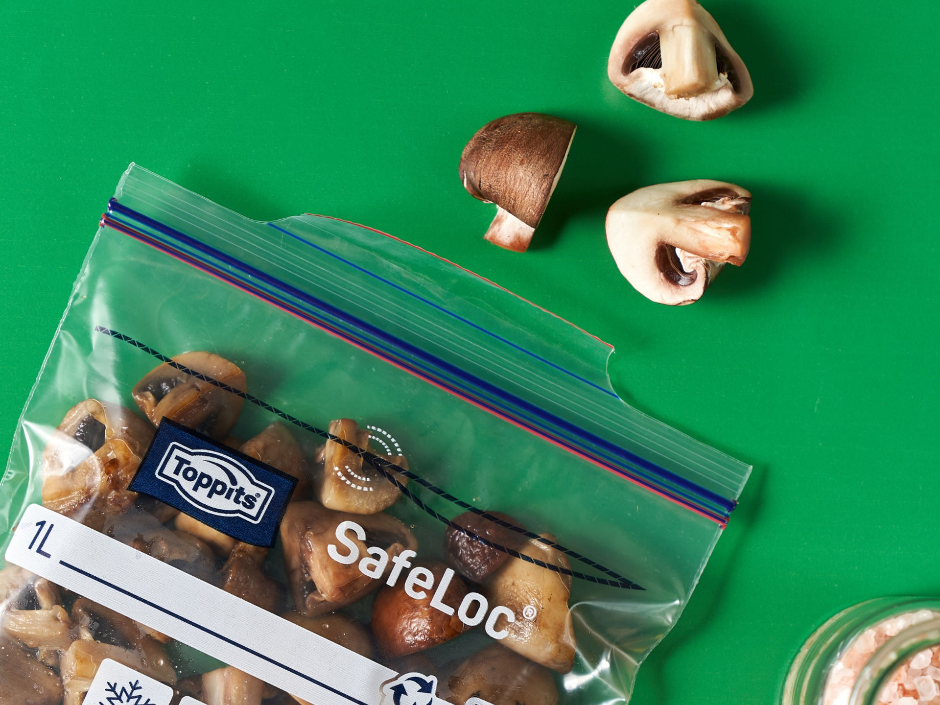 Gegarte Champignons in einem Toppits SafeLoc Beutel, daneben einzelne Pilzstücke.