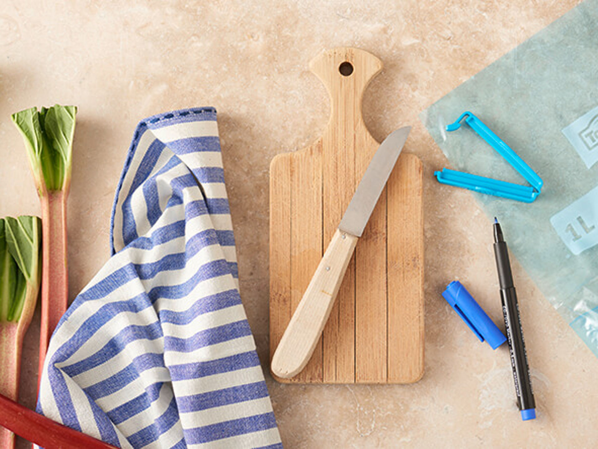 Frischer Rhabarber, Schneidebrett und Toppits Beutel mit Clip und Beschriftungsstift.
