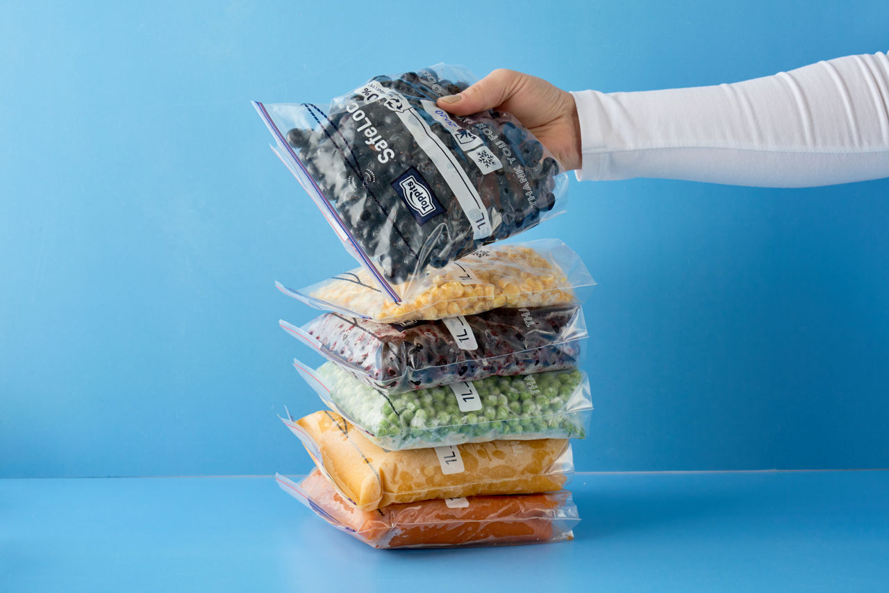 Staplade Toppits® SafeLoc® påsar fyllda med olika livsmedel hålls av en hand