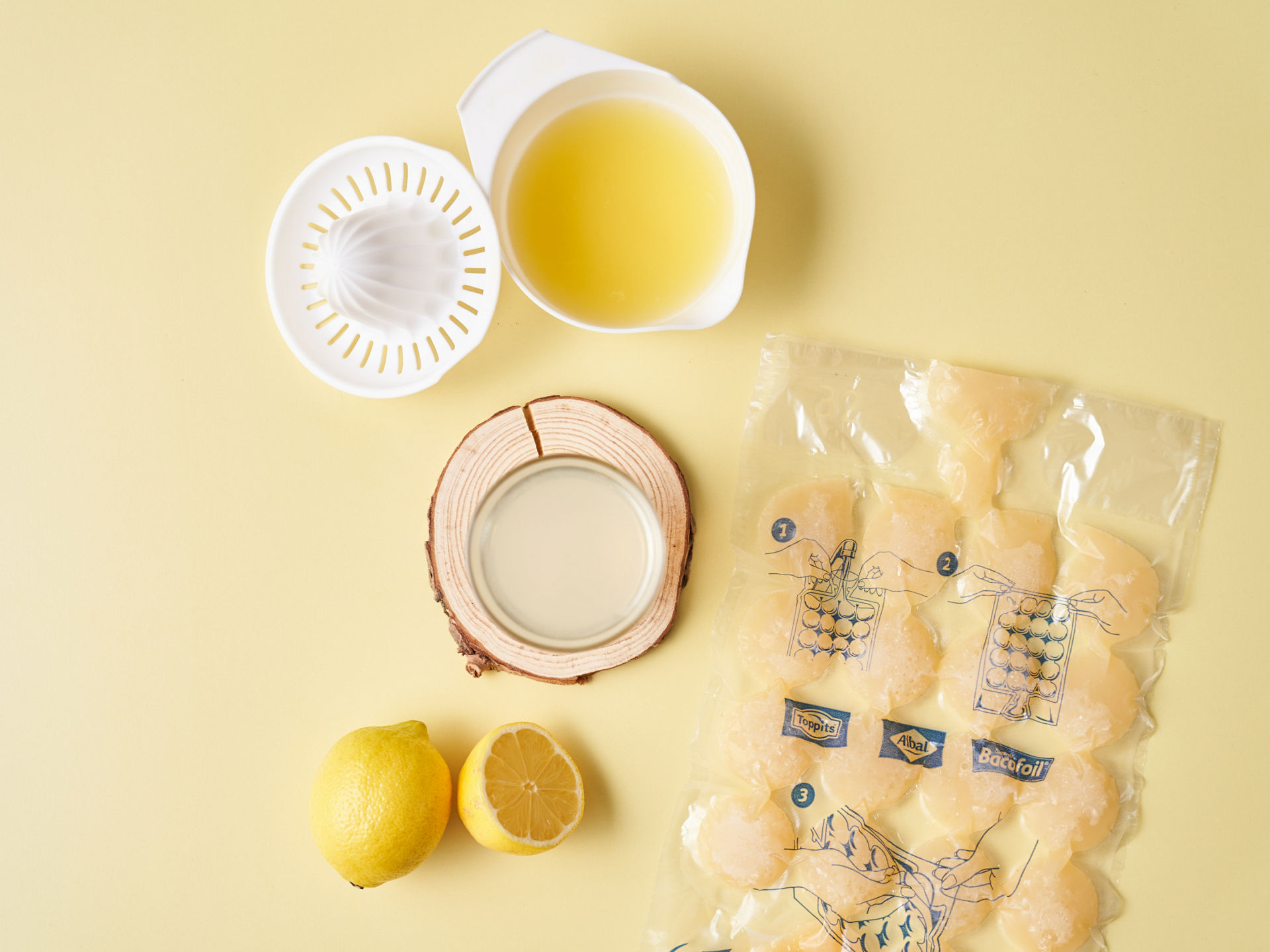 Sachet glaçons Albal rempli de jus de citron congelé, presse-citron rempli de jus et deux citrons