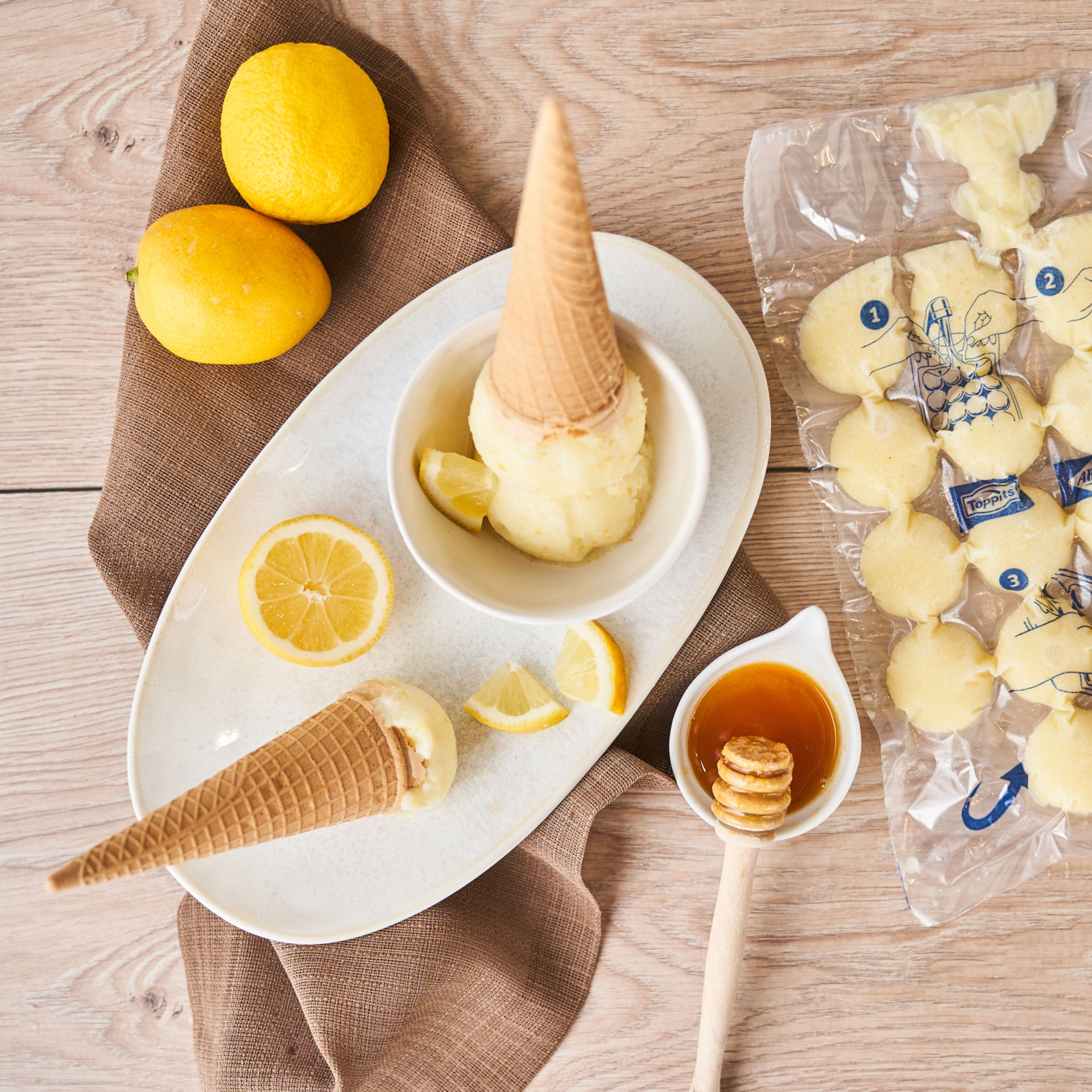 Sachet glaçons Albal rempli d'une préparation, deux glaces en cornet, deux citrons et miel