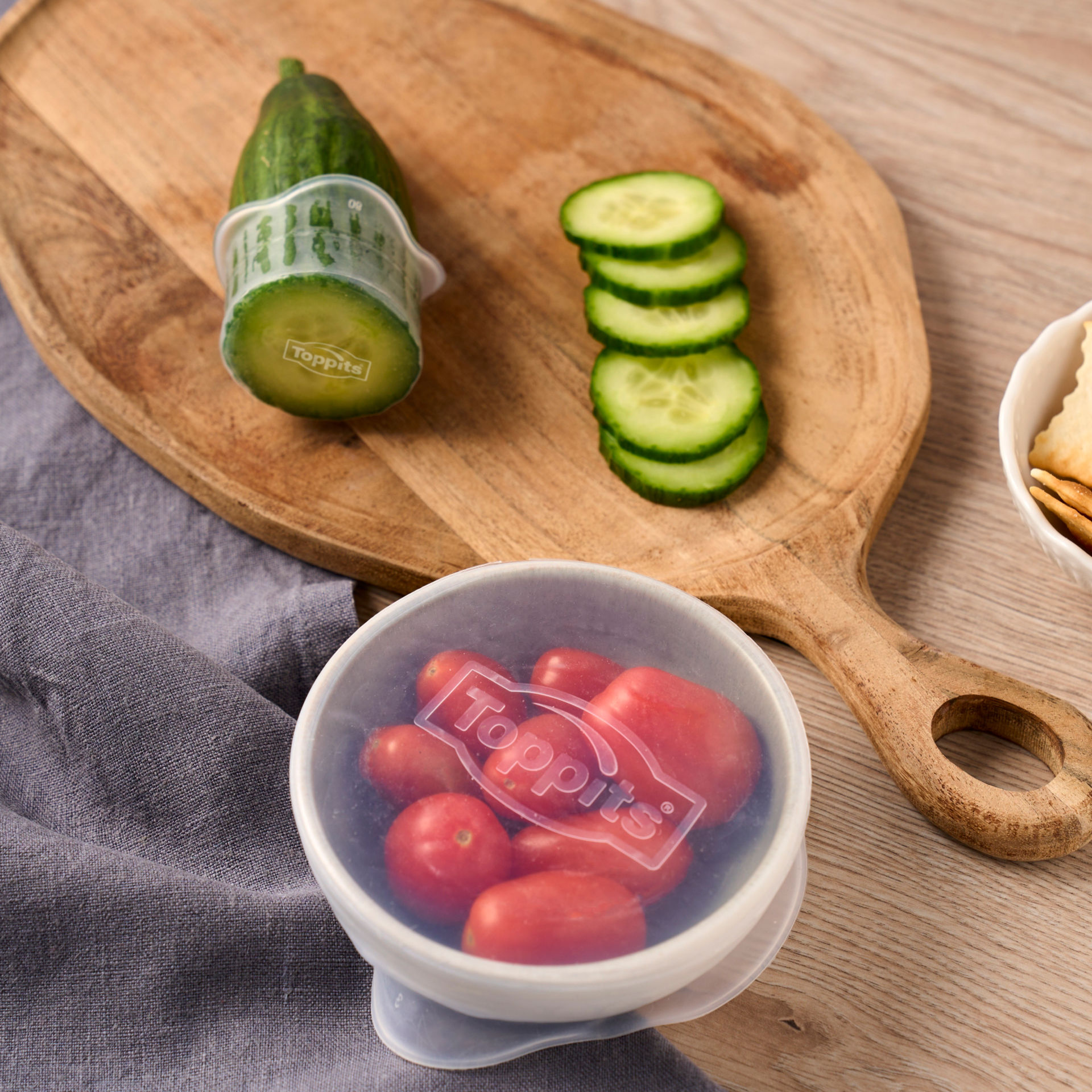 Eine Schale mit Cherrytomaten und eine angeschnittene Gurke sind mit Toppits Silikondeckel geschützt.